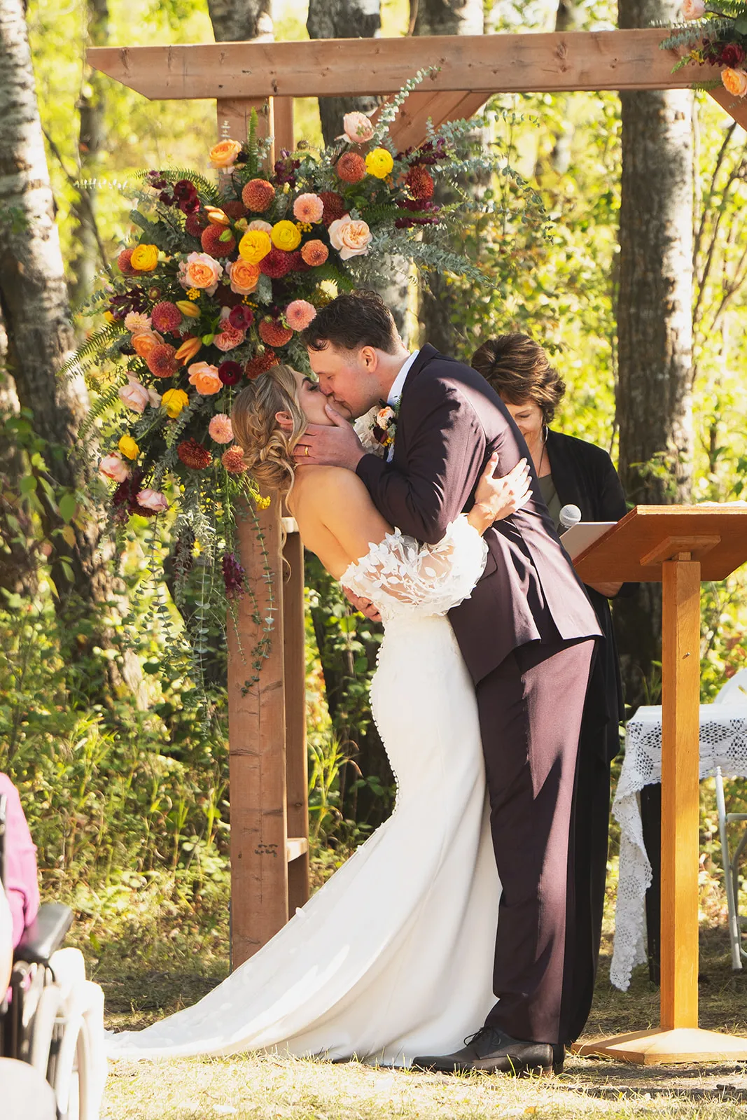 Newlyweds kissing under a floral arch