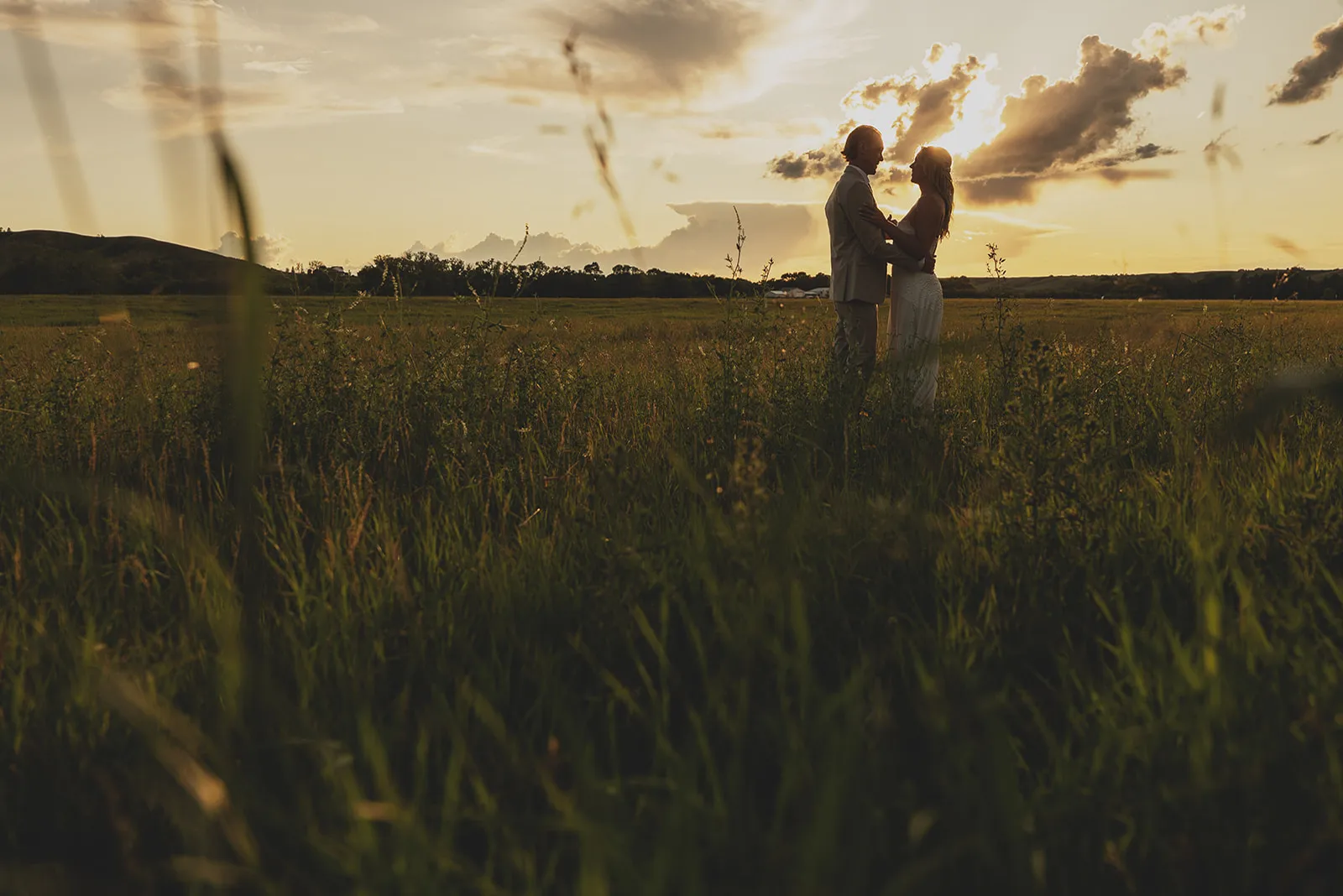 A couple silhouetted in a prairie field at sunset