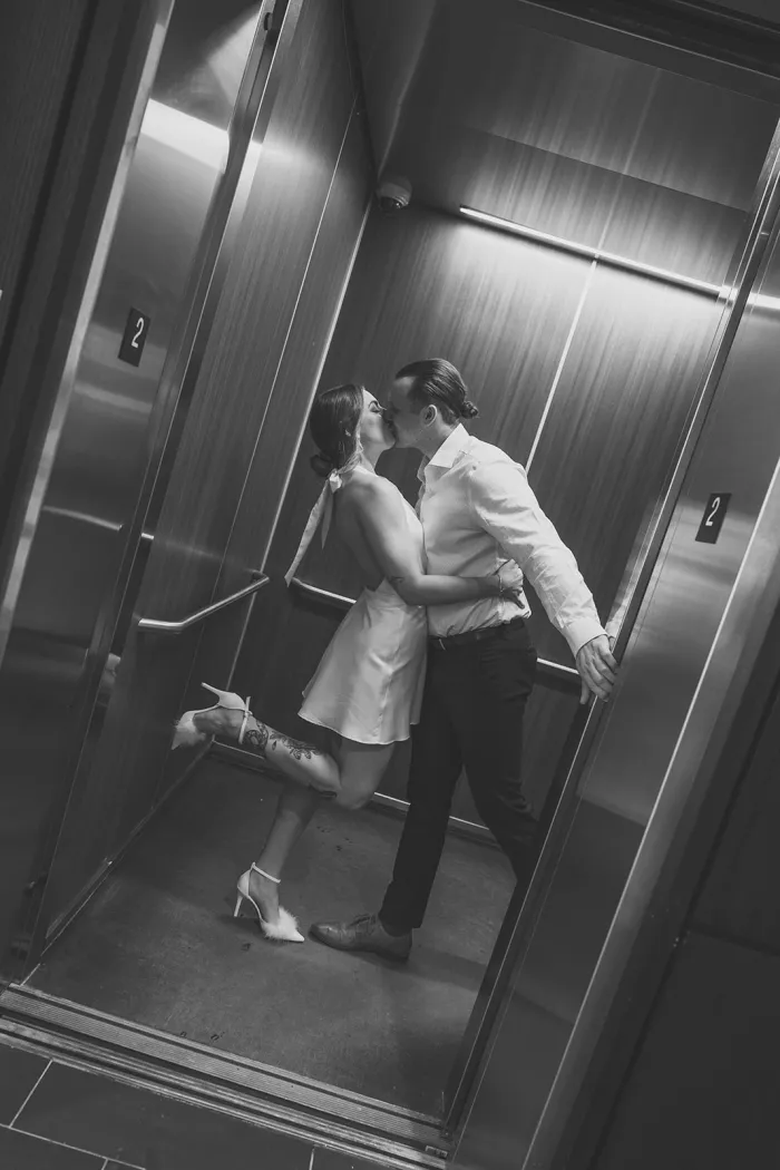 Black and white photo of a couple kissing in an elevator