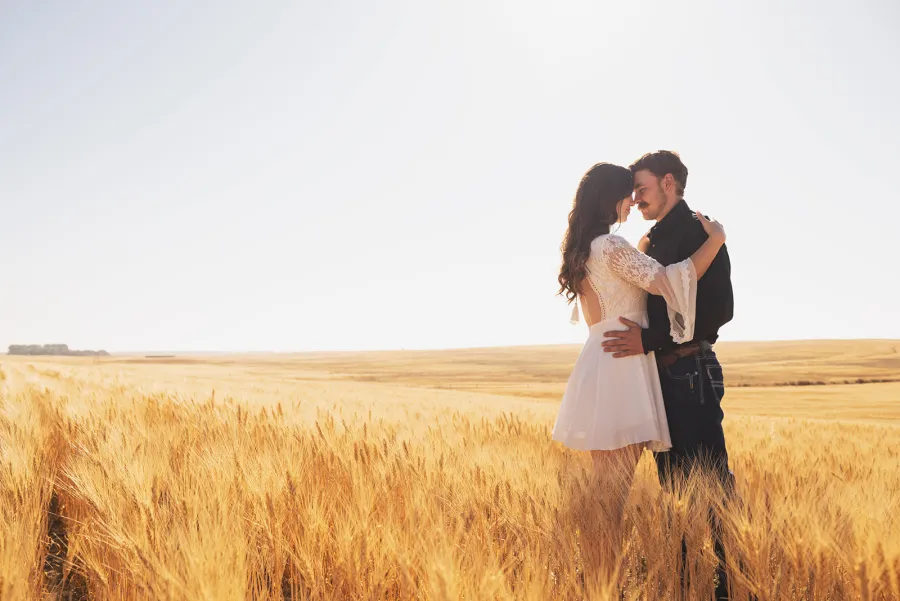 Couple forehead to forehead in a golden wheat field