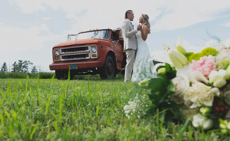 Couple beside a vintage red farm truck in summer